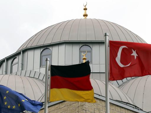 Eine europäische, eine deutsche und eine türkische Fahne (l-r) wehen am Freitag (10.09.2010) vor der Merkez-Moschee in Duisburg vor dem Beginn des Freitagsgebets. Die Debatte um die geplante Koran-Verbrennung in Florida hat die Feiertagsruhe der Muslime zum Ende des Ramadans gestört.