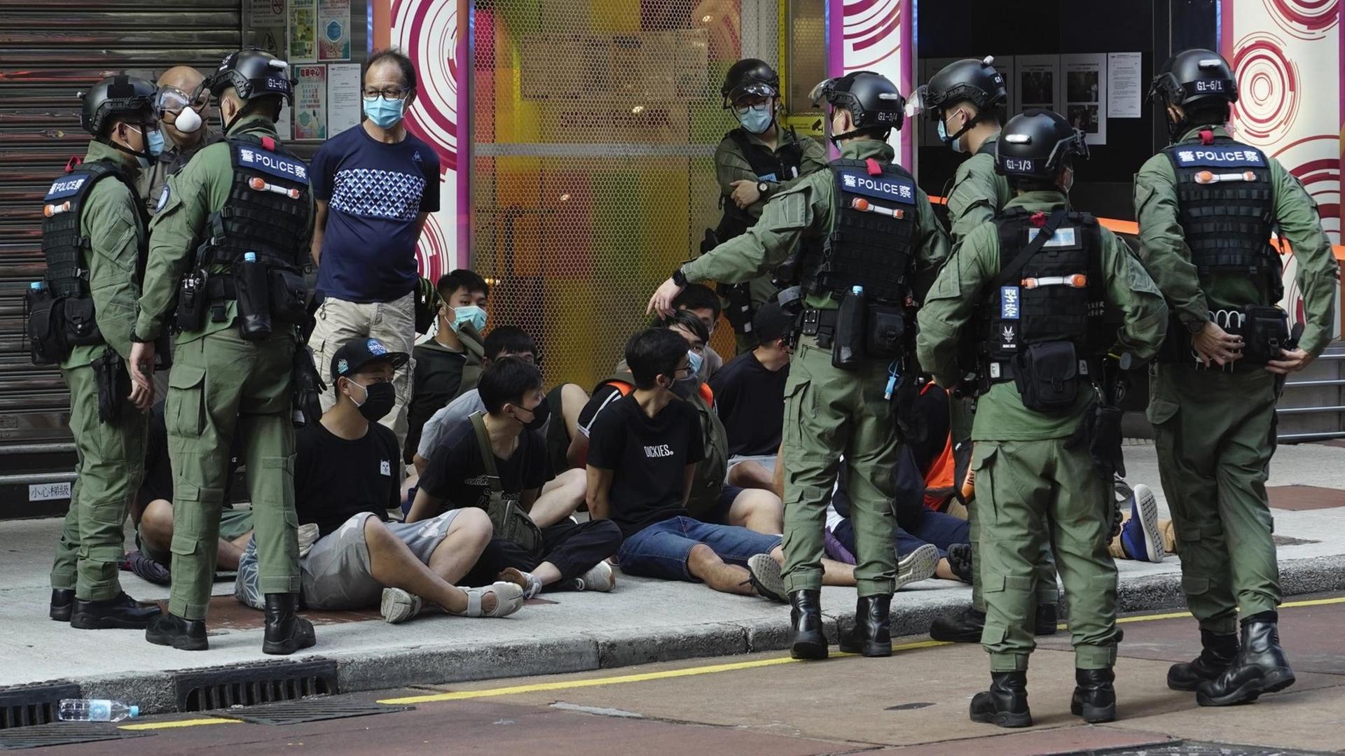 Polizisten in Hongkong nehmen Demonstranten fest, die auf dem Bürgersteig sitzen. Polizisten in Hongkong nehmen Demonstranten fest, die auf dem Bürgersteig sitzen.