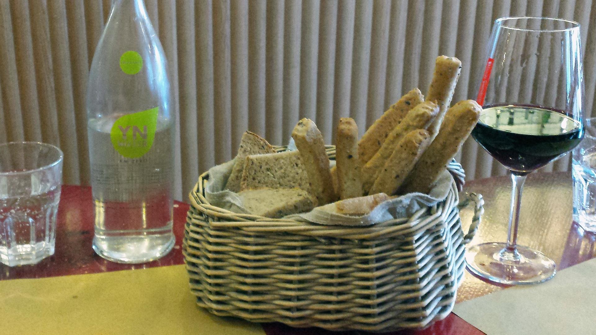 Ein Brotkorb mit einer Flasche und einem Glas Wasser, dazu ein Glas Wein. Ein Brotkorb mit einer Flasche und einem Glas Wasser, dazu ein Glas Wein.