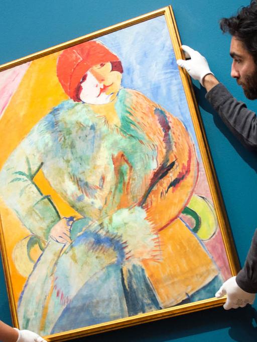 Helfer der Schirn Kunsthalle in Frankfurt am Main hängen am 23.10.2015 das Gemälde "Frau mit Pelz und rotem Hut" von Sigrid Hjertén auf.