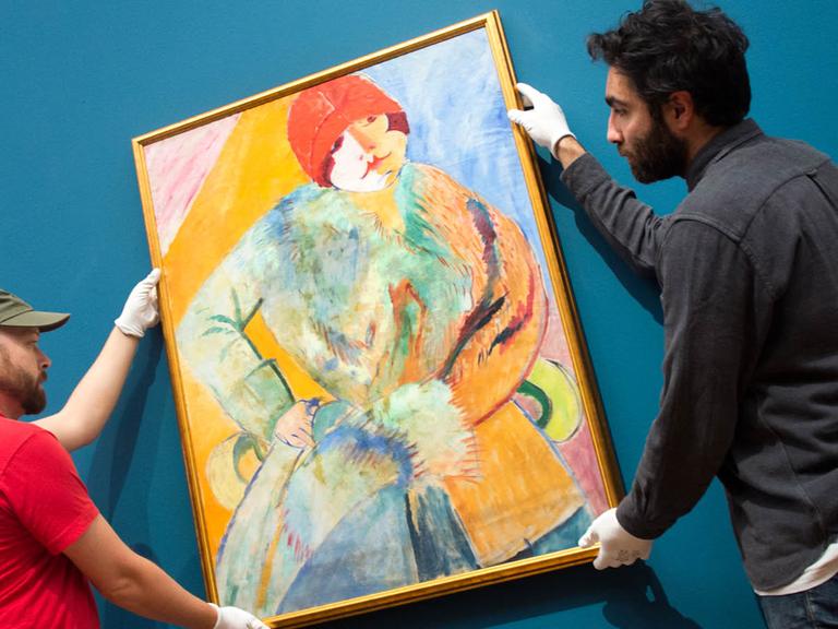 Helfer der Schirn Kunsthalle in Frankfurt am Main hängen am 23.10.2015 das Gemälde "Frau mit Pelz und rotem Hut" von Sigrid Hjertén auf.