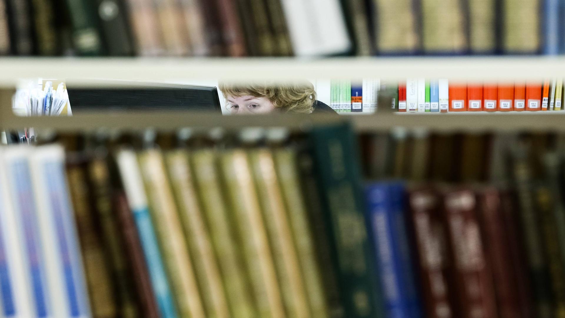 Die Augen einer Frau sind zwischen Bücherregalen in einer Bücherrei in Russland zu sehen Die Augen einer Frau sind zwischen Bücherregalen in einer Bücherrei in Russland zu sehen