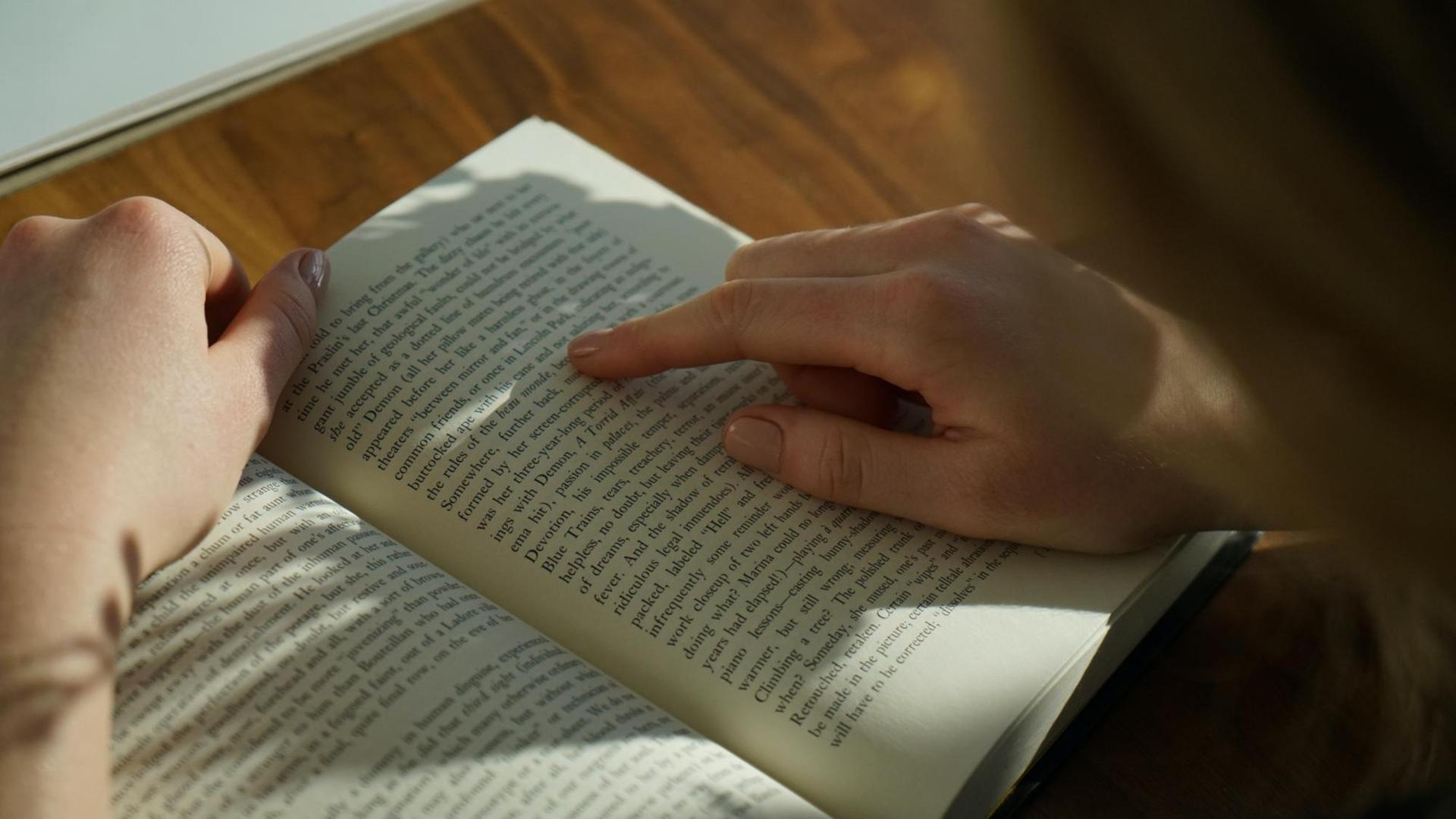 Eine Hand fährt mit dem Zeigefinger die Zeilen eines aufgeschlagenen Buches nach. Eine Hand fährt mit dem Zeigefinger die Zeilen eines aufgeschlagenen Buches nach.