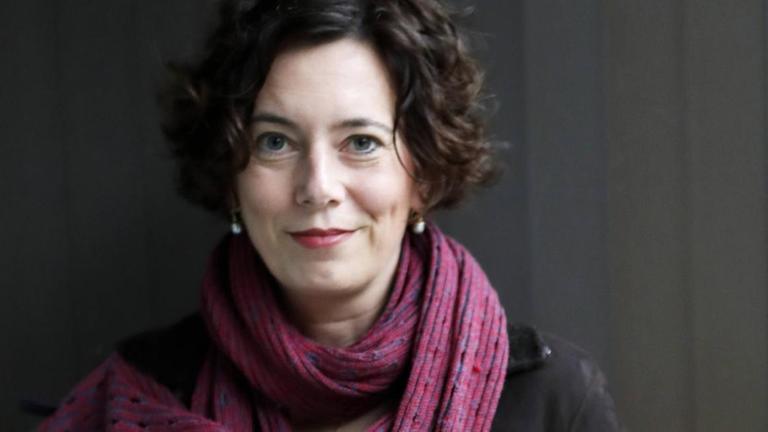 Eva Menasse blickt vor dunklem Hintergrund freundlich in die Kamera und trägt einen lila Schal. Eva Menasse blickt vor dunklem Hintergrund freundlich in die Kamera und trägt einen lila Schal.