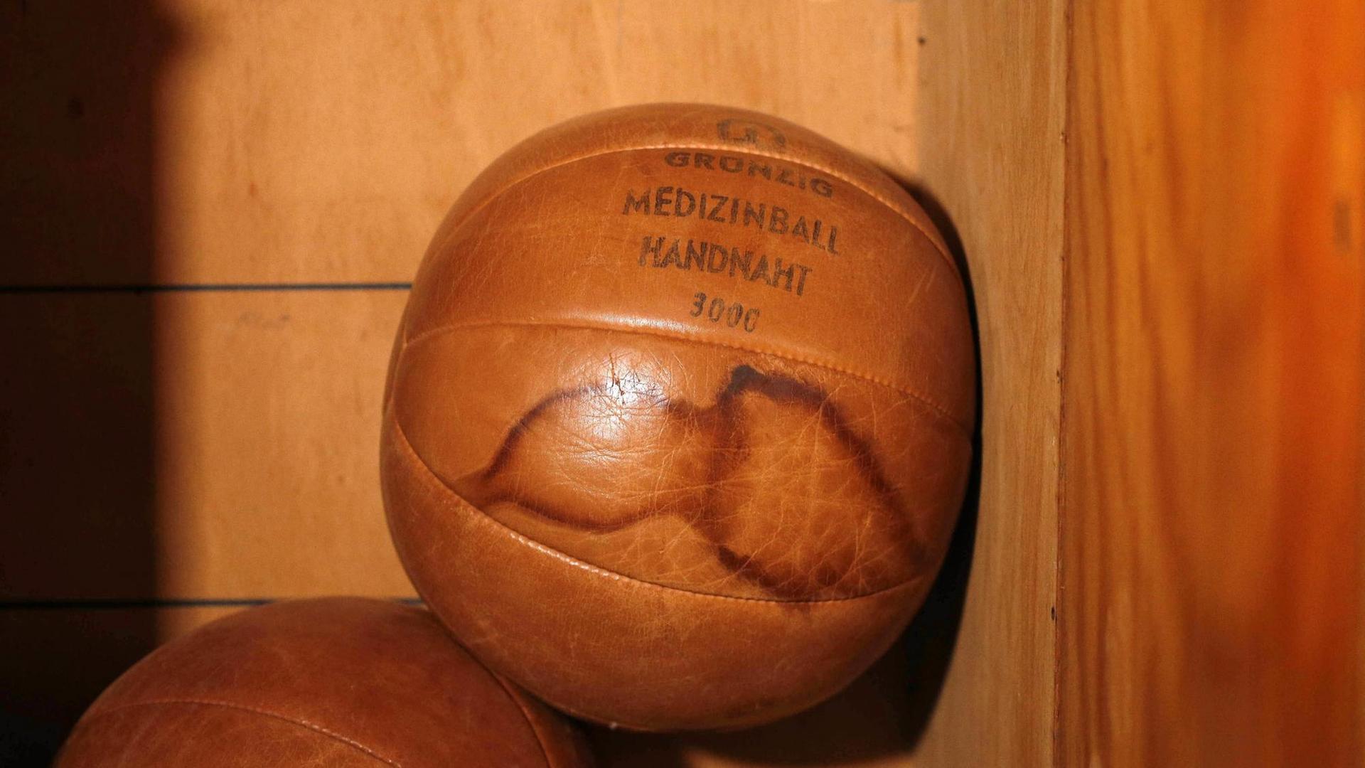 In einem Schrank liegt ein Medizinball auf einen anderen. An einer Seite des Balls sind zwei Flecken zu sehen.
