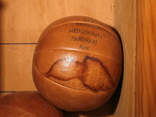 In einem Schrank liegt ein Medizinball auf einen anderen. An einer Seite des Balls sind zwei Flecken zu sehen.