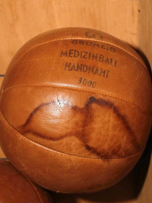 In einem Schrank liegt ein Medizinball auf einen anderen. An einer Seite des Balls sind zwei Flecken zu sehen.
