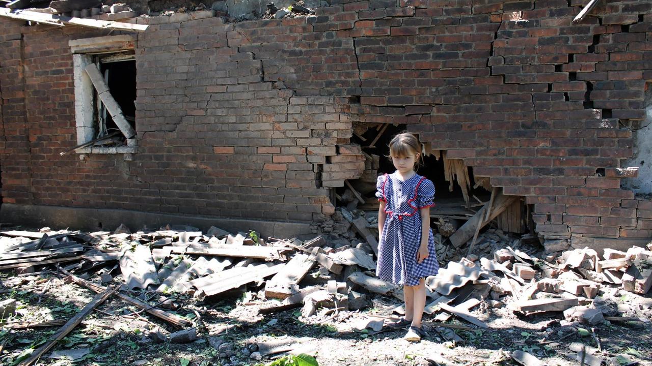 Ein Mädchen am 6.9.2015 vor einem zerstörten Haus in der Donezk-Region.