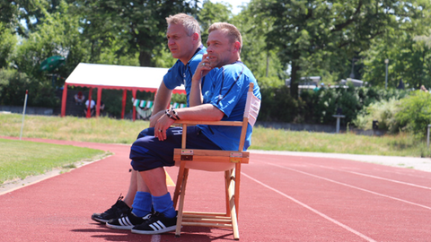 Thomas "Icke" Häßler sitzt auf einem Stuhl am Rand eines Fussballfeldes.