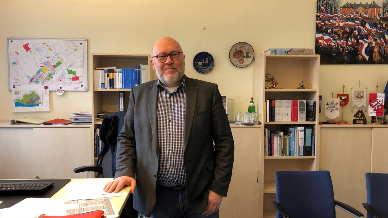 Martin Schmedtje steht neben seinem Schreibtisch in seinem Büro. Martin Schmedtje steht neben seinem Schreibtisch in seinem Büro.