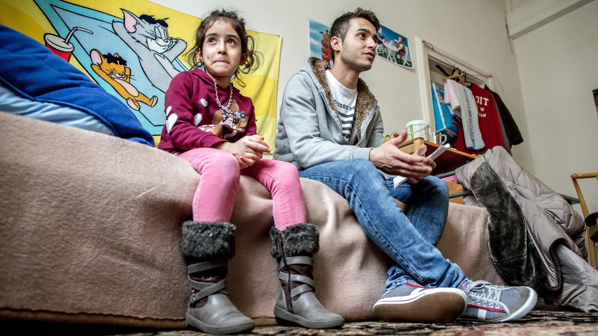 Zwei geflüchtete Geschwister aus Syrien sitzen auf dem Bett in ihrer Unterkunft. Zwei geflüchtete Geschwister aus Syrien sitzen auf dem Bett in ihrer Unterkunft.