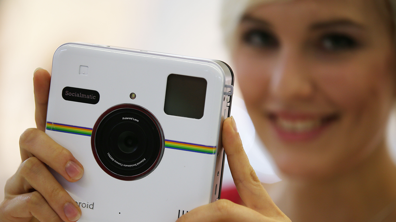 Eine Frau schaut sich auf der Messe Photokina die Polaroid Kamera Socialmanic an (2014). Eine Frau schaut sich auf der Messe Photokina die Polaroid Kamera Socialmanic an (2014).