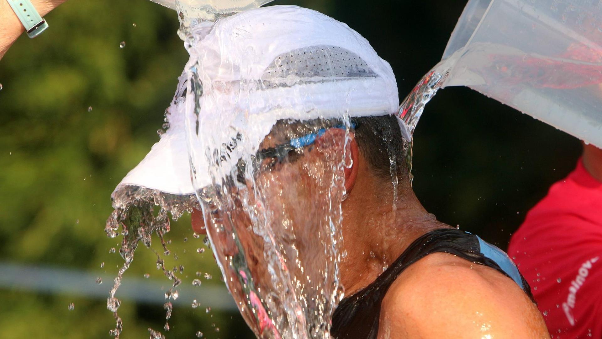Mainova Ironman 2019 in Frankfurt, Hessen, Deutschland: erschöpfter Athlet erhält an einer Verpflegungsstation während des Marathonlauf s bei drückender Hitze einen Eimer kalten Wasser s über seinen Kopf *** Mainova Ironman 2019 in Frankfurt, Hesse, Germany exhausted athlete receives a bucket of cold water s over his head at a refreshment station during the marathon run s in oppressive heat Mainova Ironman 2019 in Frankfurt, Hessen, Deutschland: erschöpfter Athlet erhält an einer Verpflegungsstation während des Marathonlauf s bei drückender Hitze einen Eimer kalten Wasser s über seinen Kopf *** Mainova Ironman 2019 in Frankfurt, Hesse, Germany exhausted athlete receives a bucket of cold water s over his head at a refreshment station during the marathon run s in oppressive heat