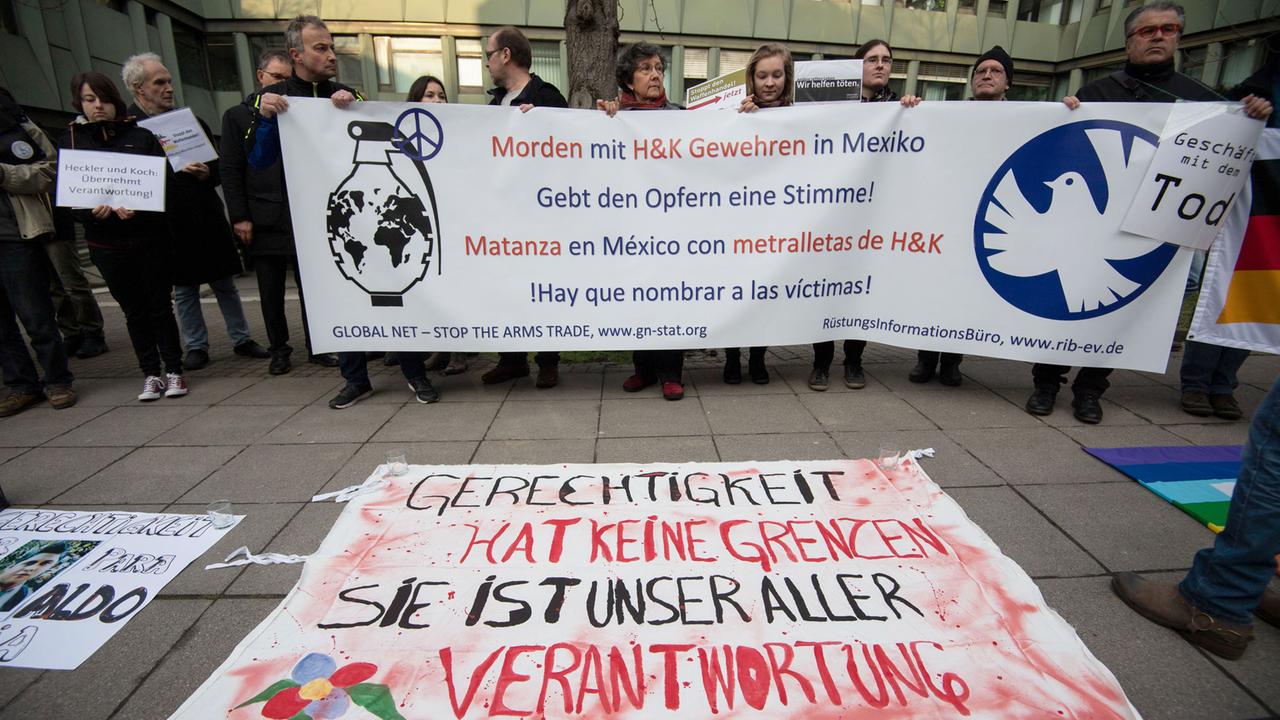 Demonstranten stehen vor der Urteilsverkündung im Prozess gegen ehemalige Mitarbeiter von Heckler & Koch vor dem Landgericht Stuttgart.