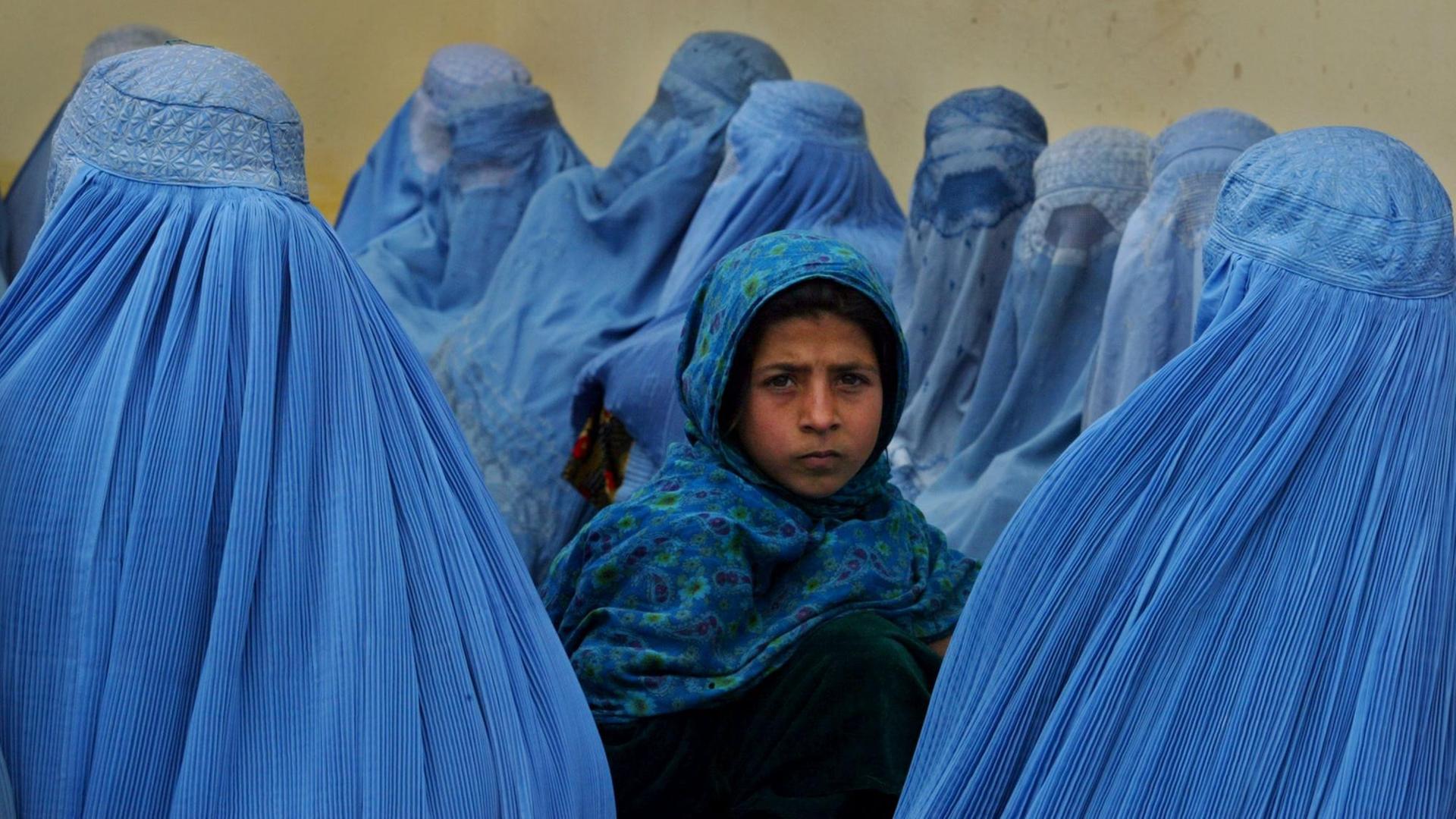 Ein kleines Mädchen umringt von afghanischen Frauen in blauen Burkas warten vor einer Klinik in der afghanischen Stadt Kalakan auf medizinische Hilfe. Ein kleines Mädchen umringt von afghanischen Frauen in blauen Burkas warten vor einer Klinik in der afghanischen Stadt Kalakan auf medizinische Hilfe.