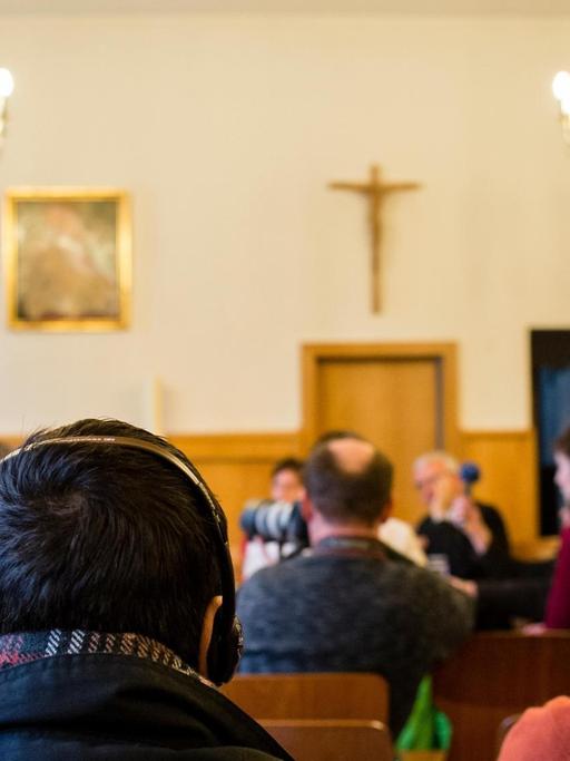 Ein Flüchtling hört sich am 21.03.2016 die Übersetzung eines Pressegespräches zu christlichen Flüchtlingen und ihrer Unterbringung in der katholischen Kirche St. Elisabeth in Berlin, in Arabisch über Kopfhörer an.