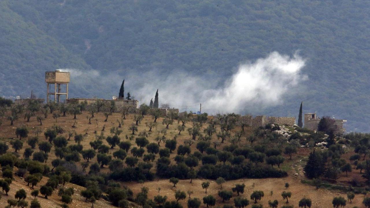Das Bild zeigt Rauch, der über einer hügeligen Landschaft im Nordwesten Syriens nach Artilleriebeschuss durch die türkische Armee aufsteigt. Das Bild zeigt Rauch, der über einer hügeligen Landschaft im Nordwesten Syriens nach Artilleriebeschuss durch die türkische Armee aufsteigt.