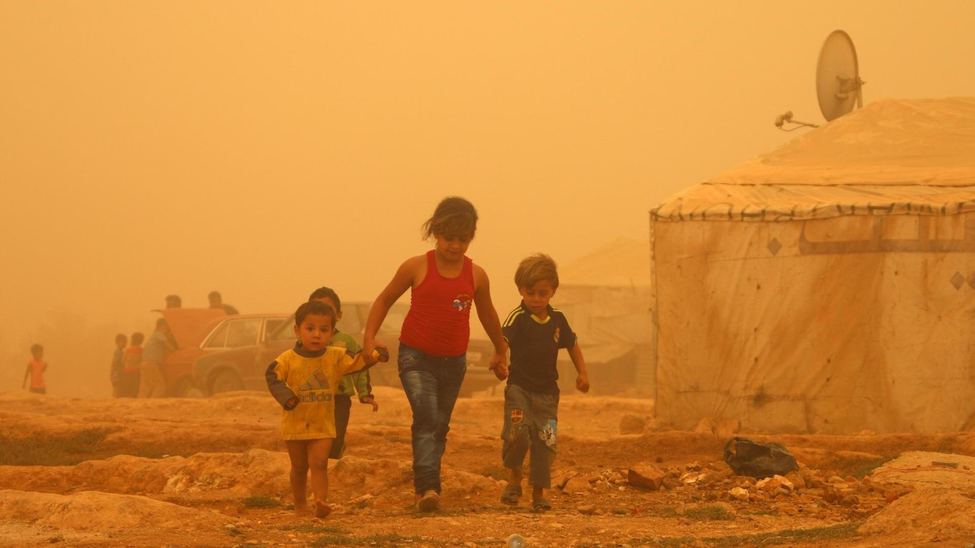 Zu sehen sind drei Kinder in einem Flüchtlingslager bei Baalbek im Libanon, die Luft ist wegen eines Sandsturms gelb. Zu sehen sind drei Kinder in einem Flüchtlingslager bei Baalbek im Libanon, die Luft ist wegen eines Sandsturms gelb.