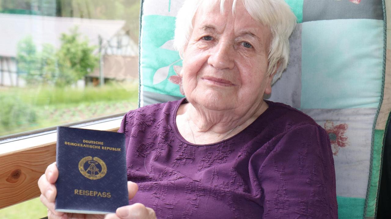 Eine ältere Frau hält ihren DDR-Reisepass in die Kamera.