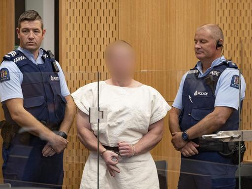 Der Attentäter steht verpixelt zwischen zwei Polizisten in einem Gerichtssaal im neuseeländischen Christchurch.