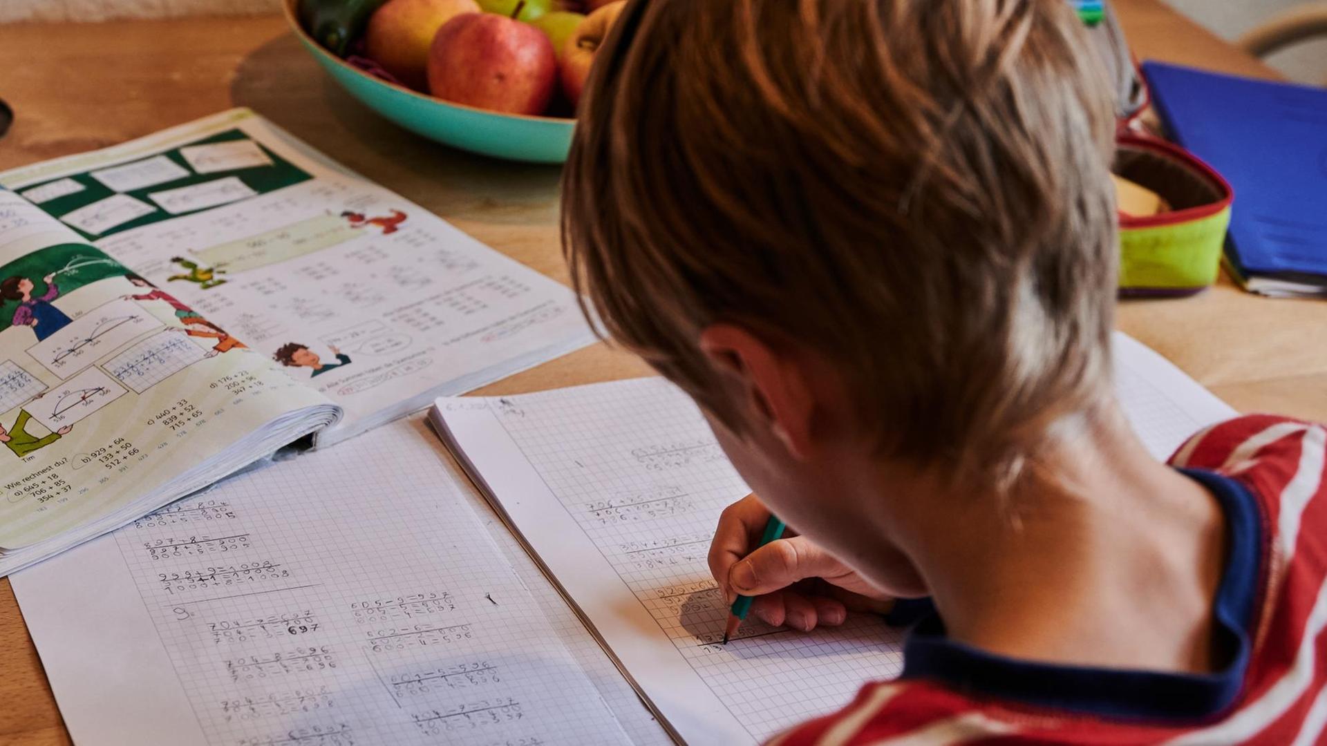 Ein Grundschüler sitzt zuhause in der Küche und rechnet in seinem Schulheft. Bund und Länder haben sich auf die Verlängerungen des Lockdowns bis zum 31.1.2021 geeinigt. Bis dahin bleiben Schulen und Kitas geschlossen. Ein Grundschüler sitzt zuhause in der Küche und rechnet in seinem Schulheft. Bund und Länder haben sich auf die Verlängerungen des Lockdowns bis zum 31.1.2021 geeinigt. Bis dahin bleiben Schulen und Kitas geschlossen.