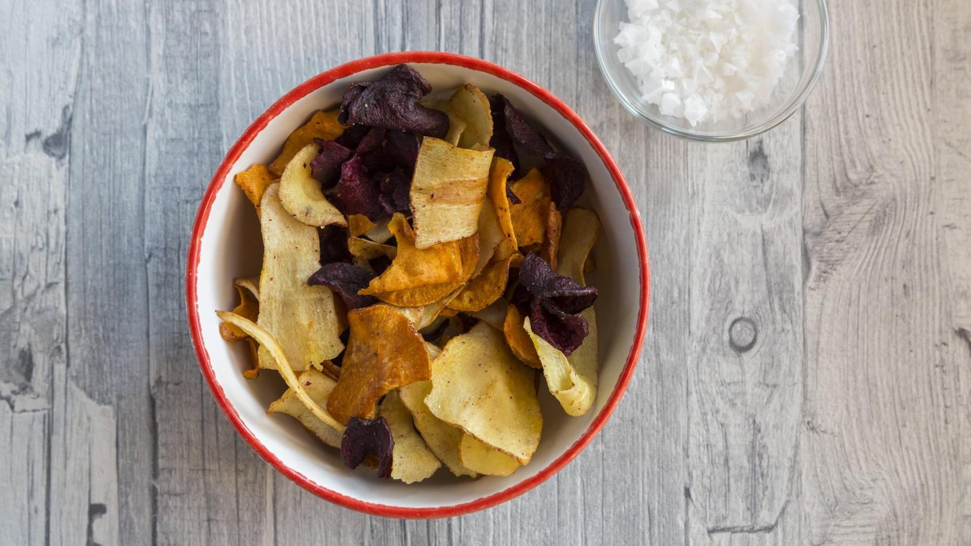 Gemüsechips in einer Schale auf einem Holztisch Gemüsechips in einer Schale auf einem Holztisch