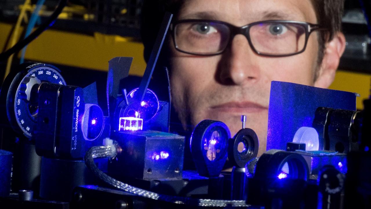 Christian Lisdat im Labor der Physikalisch-Technischen Bundesanstalt hinter einer optischen Uhr. Eines Tages könnten optische Uhren die Cäsium-Atomuhren ablösen.