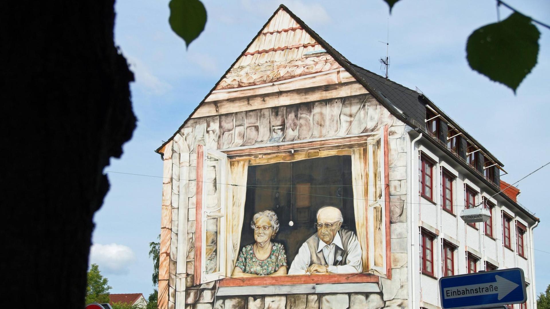 Ein Wandbild an einer Hausfassade in Bremen zeigt ein altes Ehepaar beim Blick aus dem Fenster auf den Rembertikreisel.