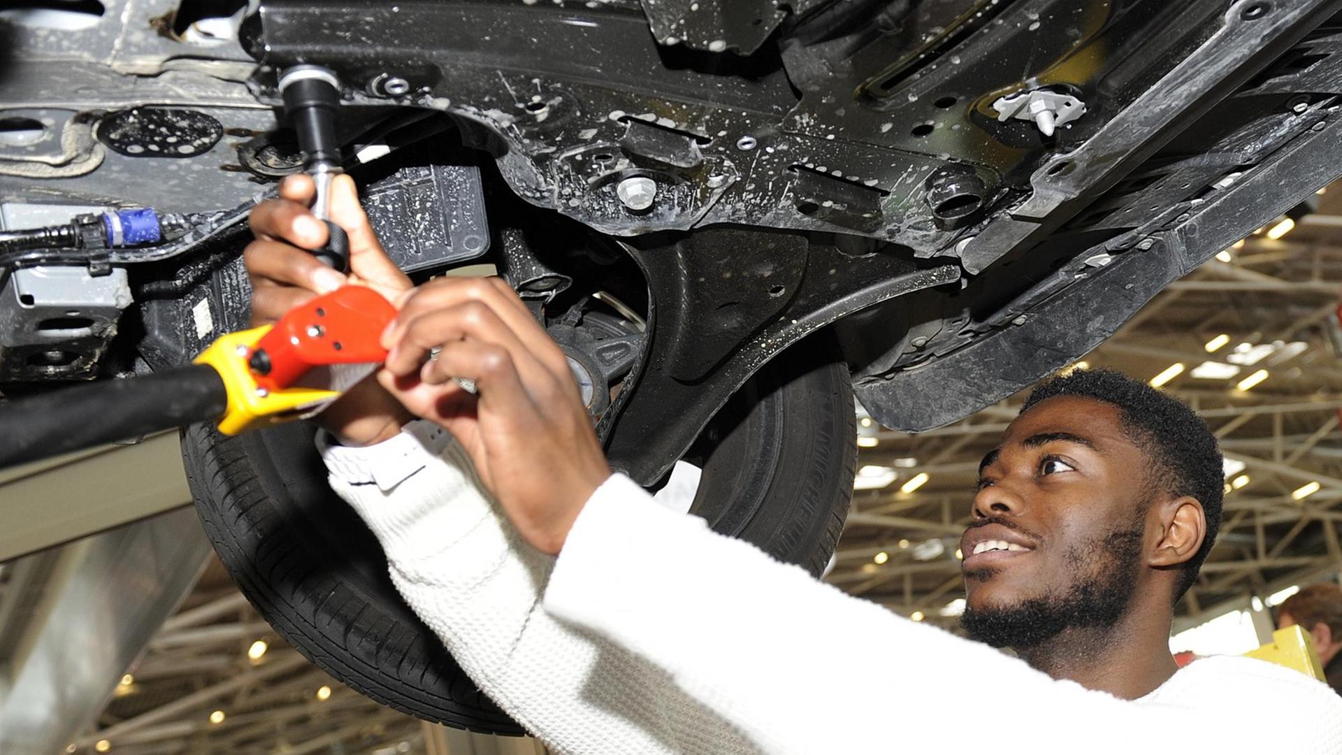 Ein Flüchtling schraubt bei seiner Ausbildung zum KFZ-Mechaniker am Unterboden eines PKW / anlässlich der Internationalen Handwerksmesse 2016 in München Ein Flüchtling schraubt bei seiner Ausbildung zum KFZ-Mechaniker am Unterboden eines PKW / anlässlich der Internationalen Handwerksmesse 2016 in München