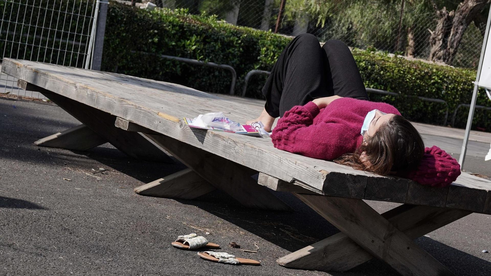 Eine Frau mit Maske liegt draußen in der Sonne Eine Frau mit Maske liegt draußen in der Sonne