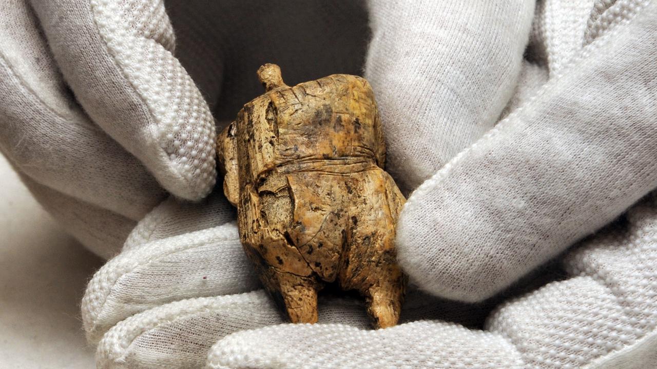Ein Archäologe hält die Venus von Schelklingen, eine ca. 40.000 Jahre Kleinst-Skulptur, die auf der Schwäbischen Alb in der Felshalle gefunden wurde, in Händen.