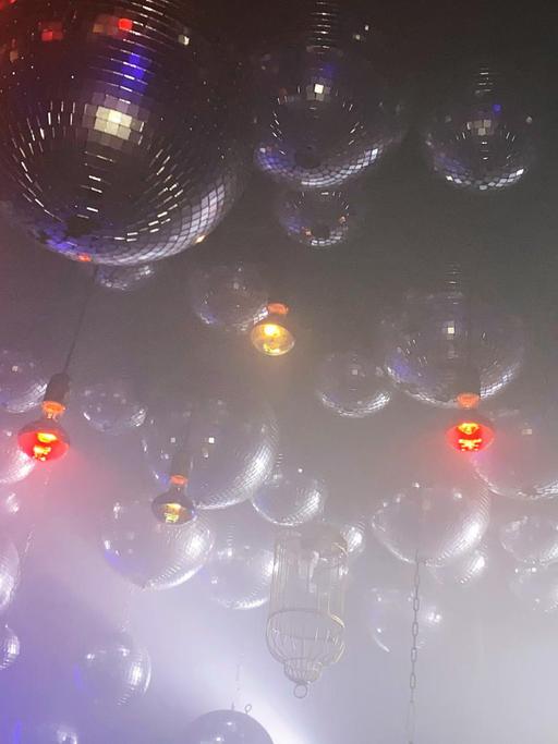Viele Discokugeln im künstlichen Nebel, hängen an der Decke des Berliner Clubs Wilde Renate.