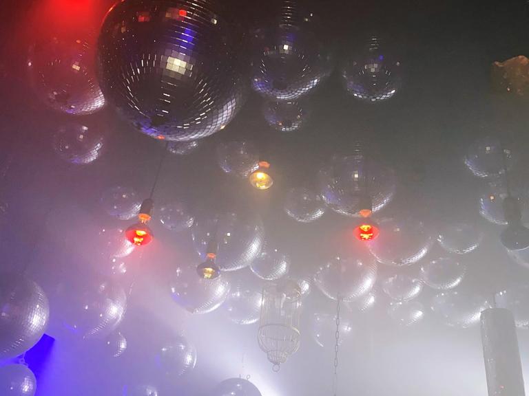 Viele Discokugeln im künstlichen Nebel, hängen an der Decke des Berliner Clubs Wilde Renate.