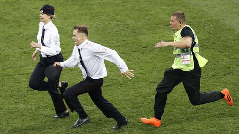 Ein Ordner rennt zwei als Polizisten verkleideten Flitzern beim Fußball-WM-Finale in Moskau hinterher.