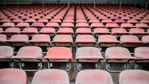 Sie sehen die leere Tribüne eines Stadions mit roten Kunststoffsitzen