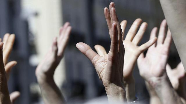 Demonstranten der spanischen 15-M Bewegung heben ihre Hände in die Luft.