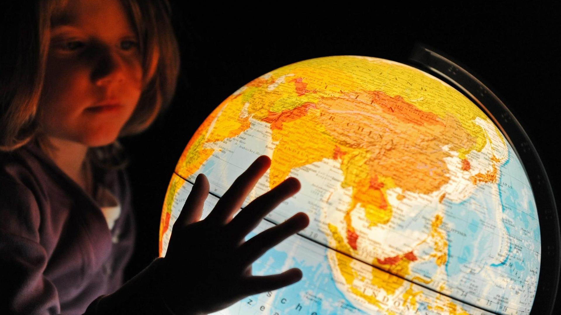 Ein kleines Mädchen betrachtet einen beleuchteten Globus, aufgenommen am 13.12.2009 in Straubing (Niederbayern).