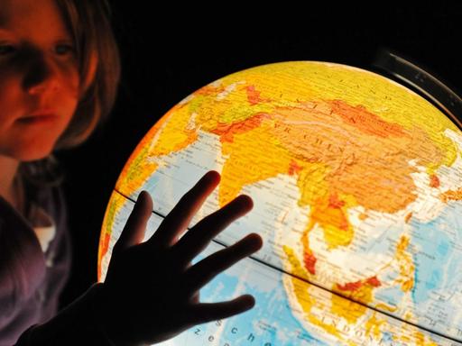 Ein kleines Mädchen betrachtet einen beleuchteten Globus, aufgenommen am 13.12.2009 in Straubing (Niederbayern).