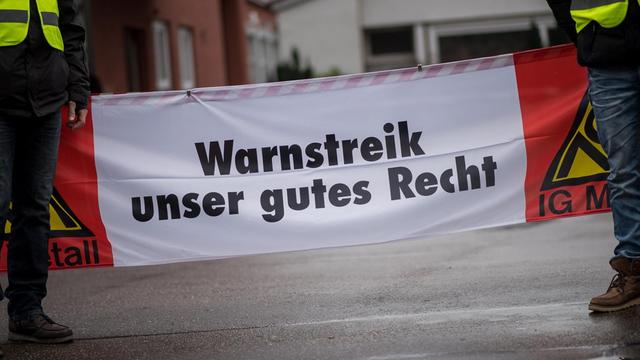 Arbeiter stehen während einem 24-stündigen Warnstreik bei der Firma Intex vor einem Banner mit der Aufschrift "Warnstreik unser gutes Recht". Ganztägige Warnstreiks der Metall- und Elektroindustrie finden in ganz Baden-Württemberg statt.