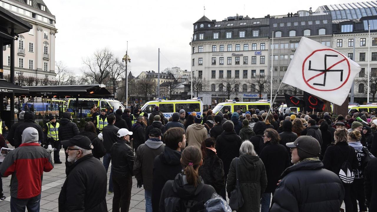 Auf einem Platz in Stockholm demonstrieren Menschen gegen Rassismus und Fremdenfeindlichkeit. Ein Banner mit einem durchgestrichenen Hakenkreuz wird hochgehalten. Auf einem Platz in Stockholm demonstrieren Menschen gegen Rassismus und Fremdenfeindlichkeit. Ein Banner mit einem durchgestrichenen Hakenkreuz wird hochgehalten.