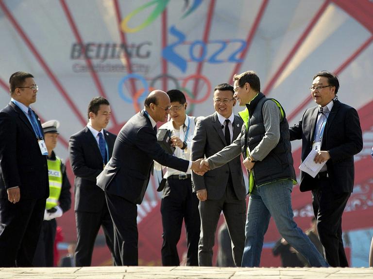 Alexander Zhukov (3.v.r.), Leiter der International Olympic Committee's Evaluation Commission, schüttelt einem Mitglied des Komitees der Olympischen Spiele 2022 in Peking die Hände vor dem National Aquatics Center.