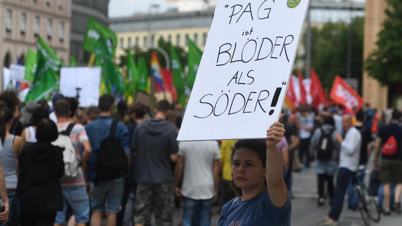 10.05.2018, Bayern, München: Eine Demonstrantin hält ein Plakat mit der Aufschrift «PAG ist blöder als Söder» bei einer Demonstation gegen das neue bayerische Polizeiaufgabengesetz (PAG). Kritiker monieren, dass die Polizei durch das Gesetz zu weitreichende Befugnisse bei der Überwachung hat. Foto: Felix Hörhager/dpa | Verwendung weltweit 10.05.2018, Bayern, München: Eine Demonstrantin hält ein Plakat mit der Aufschrift «PAG ist blöder als Söder» bei einer Demonstation gegen das neue bayerische Polizeiaufgabengesetz (PAG). Kritiker monieren, dass die Polizei durch das Gesetz zu weitreichende Befugnisse bei der Überwachung hat. Foto: Felix Hörhager/dpa | Verwendung weltweit