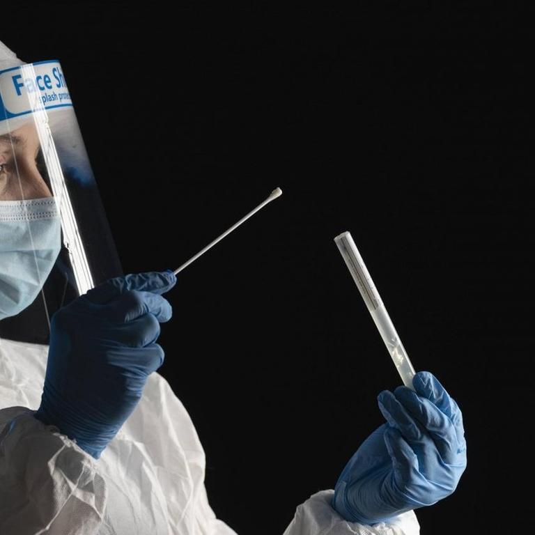 Woman in protective wear putting a swab into a tube model released Symbolfoto property released SNF00064 