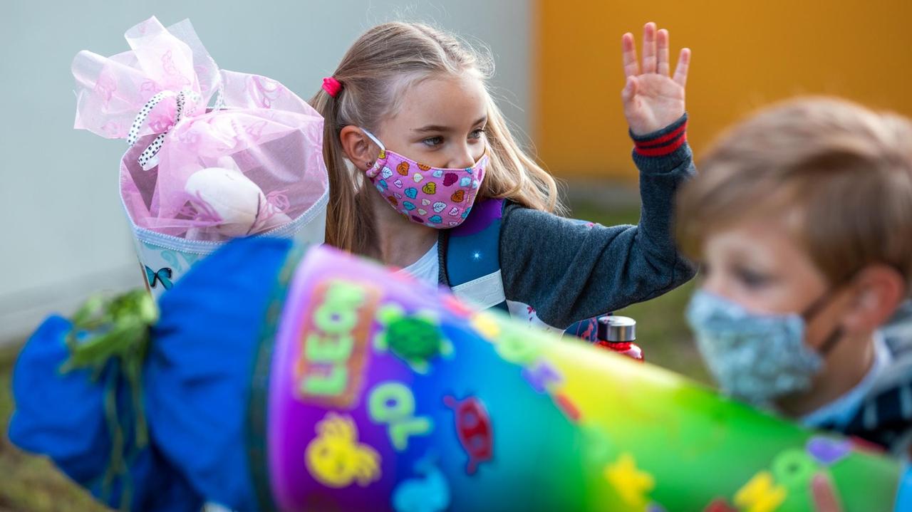 Eine Schülerin und ein Schüler mit Mundschutz halten ihre Schultüten im Arm. Eine Schülerin und ein Schüler mit Mundschutz halten ihre Schultüten im Arm.