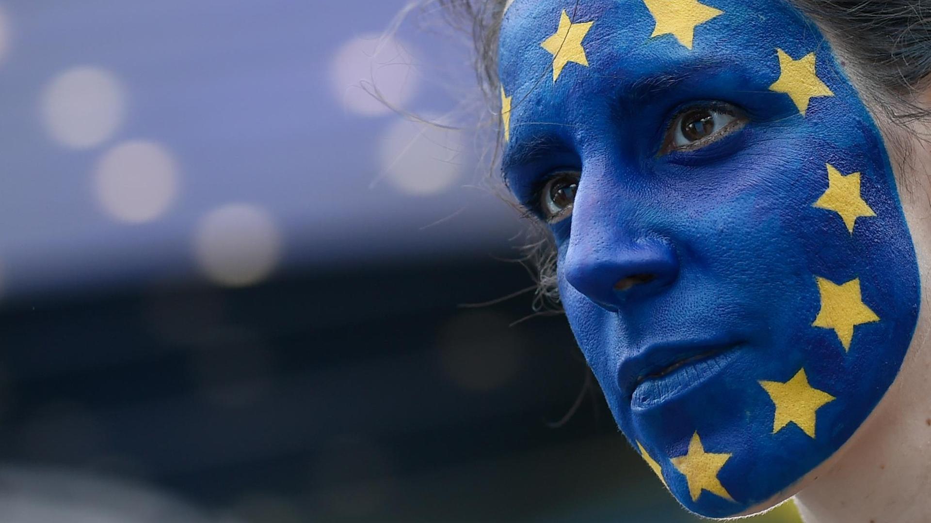 Eine Frau mit der Europaflagge im Gesicht wartet vor dem Europäischen Parlament auf die Bekanntgabe der Wahlergebnisse.