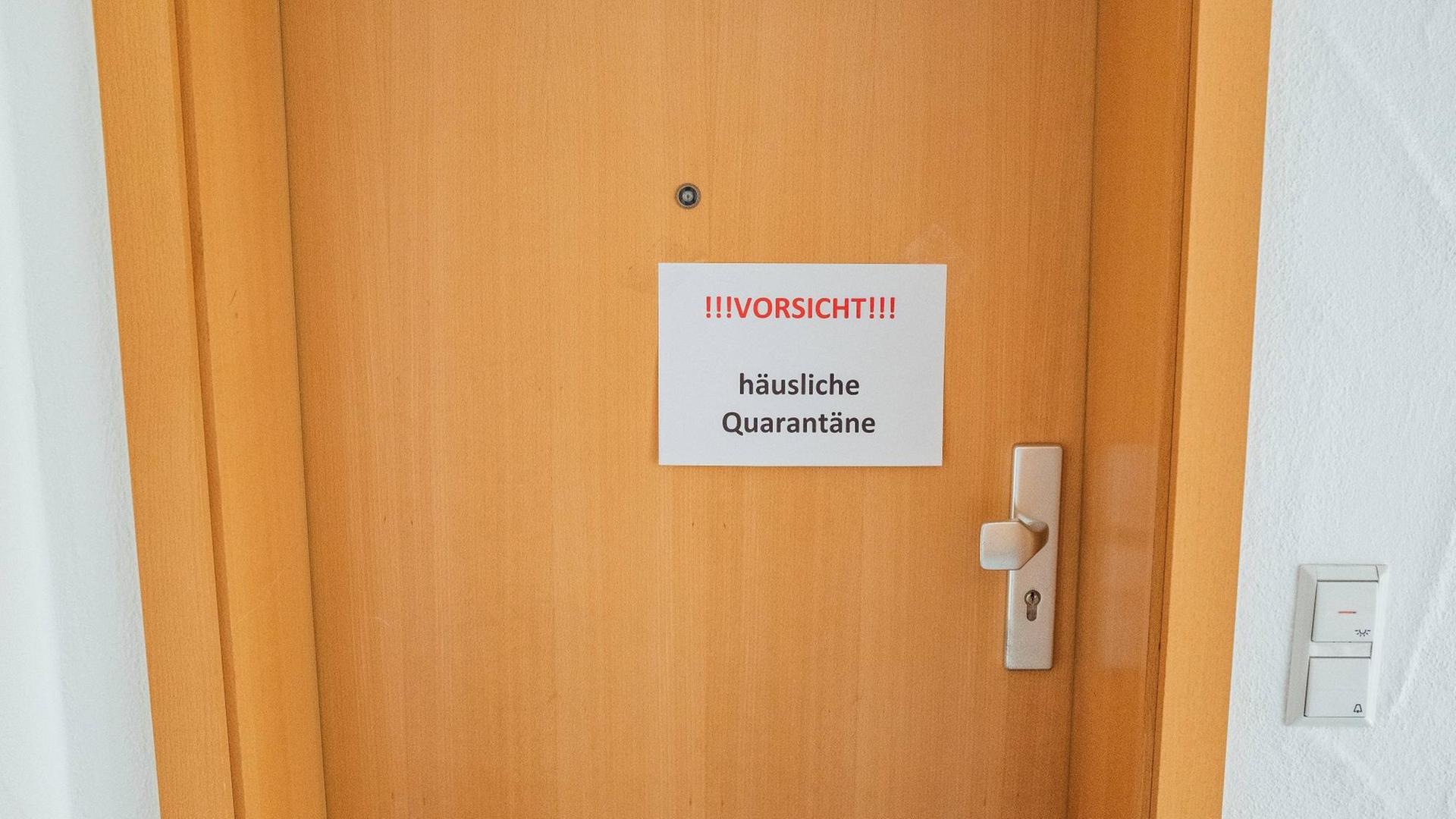 Das Foto zeigt eine Wohnungstür, an der ein Schild "Vorsicht. Häusliche Quarantäne" hängt. Das Foto zeigt eine Wohnungstür, an der ein Schild "Vorsicht. Häusliche Quarantäne" hängt.