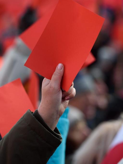 Tausende Polen demonstrieren gegen neue Gesetze mit roten Karten in den Händen.