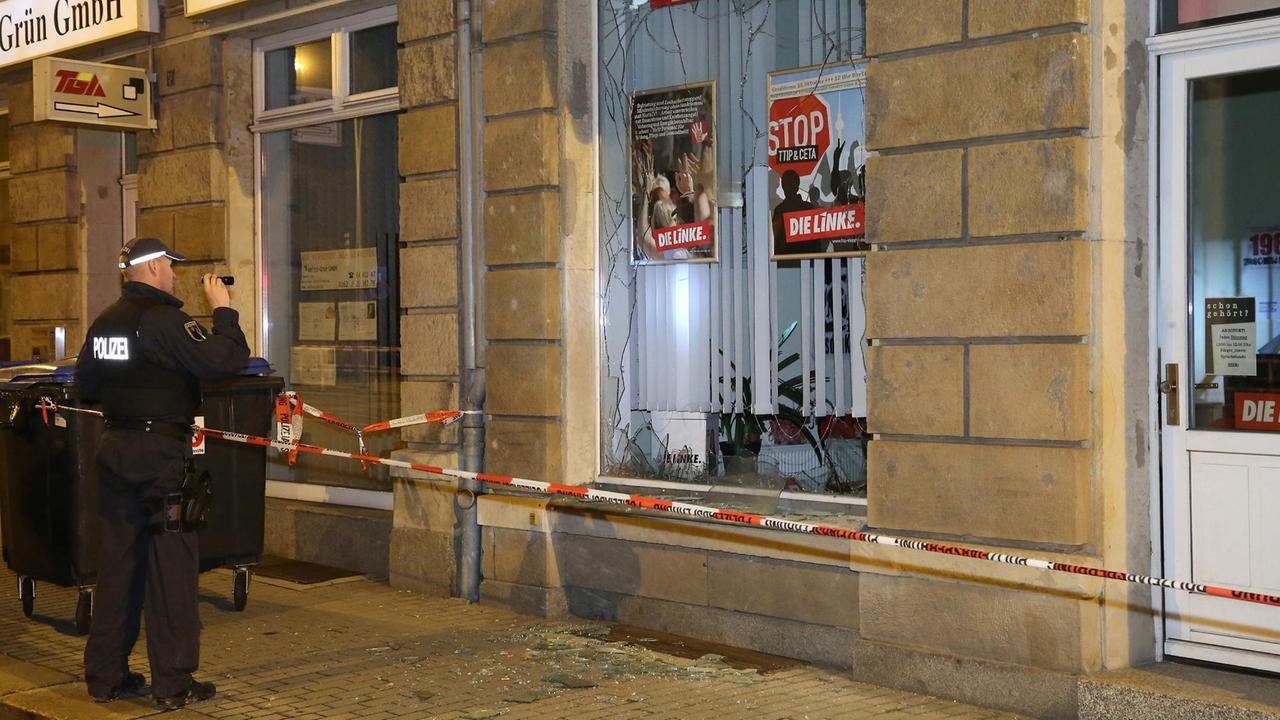 Ein Polizist steht nach dem Anschlag auf das Parteibüro der Linken in Freital 2015 vor dem Gebäude