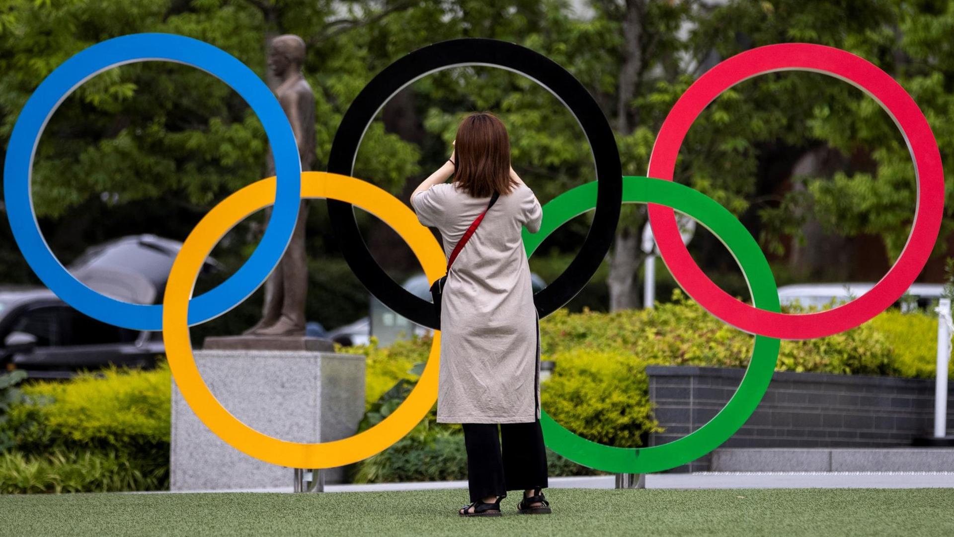 Eine Frau fotografiert die Olympischen Ringe in Tokio. Eine Frau fotografiert die Olympischen Ringe in Tokio.