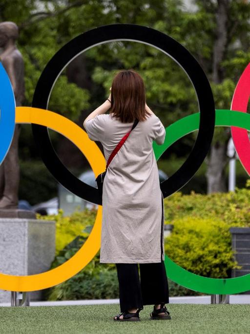 Eine Frau fotografiert die Olympischen Ringe in Tokio.